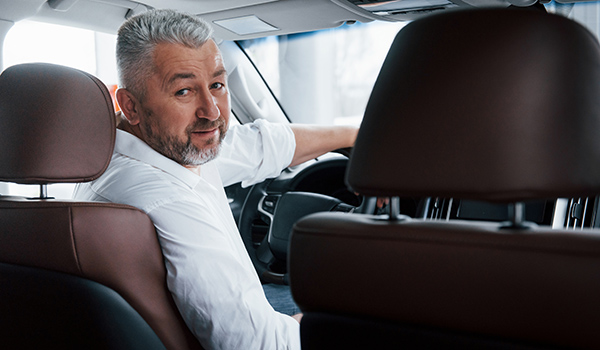 conception of success. joyful bearded man in white shirt looks into the camera while sitting in the modern car